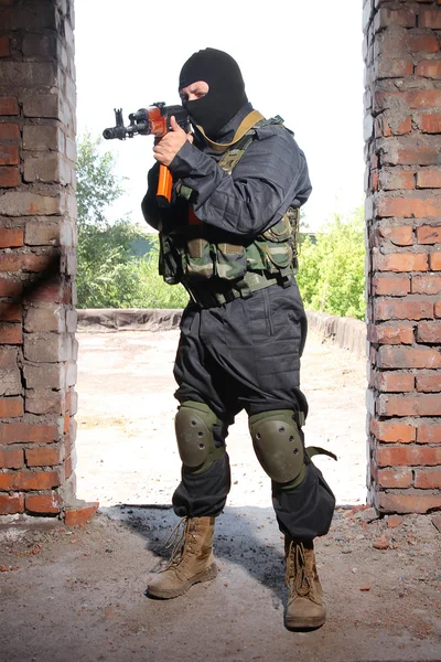 Вооруженный солдат в черной маске целится из пистолета — стоковое фото