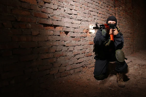 Soldado armado con máscara negra apuntando con un arma — Foto de Stock
