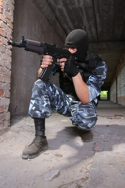 Beväpnad soldat i svart mask inriktning med en pistol — Stockfoto