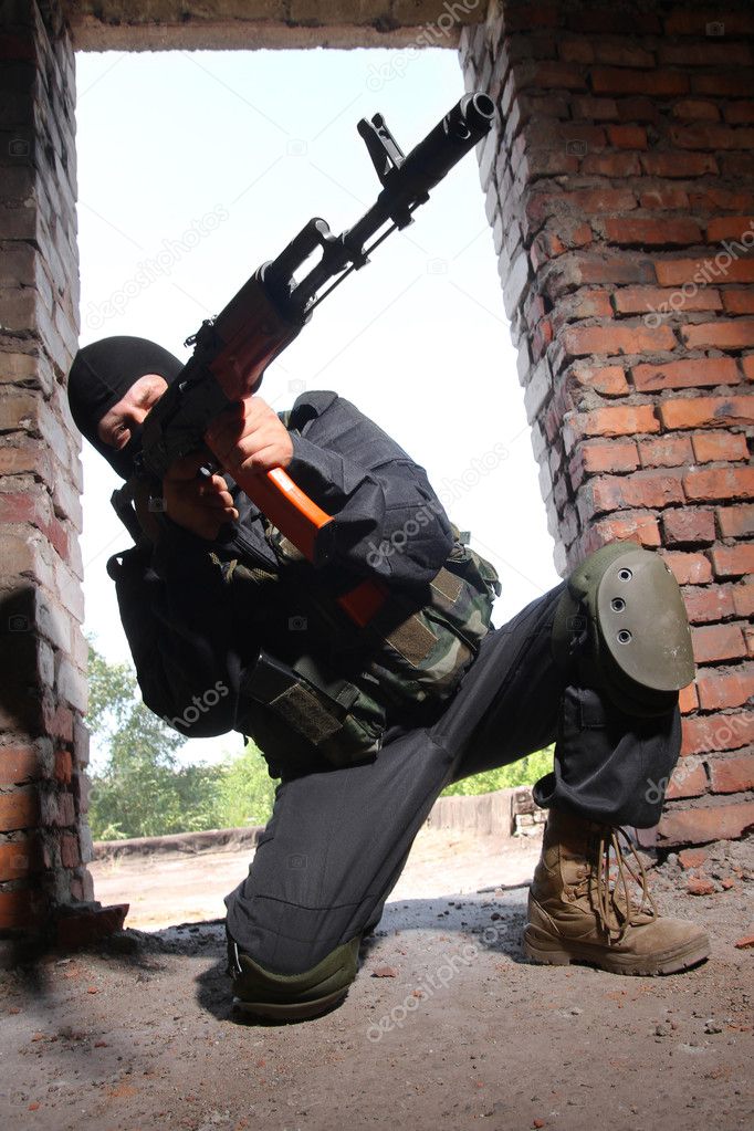 Armed soldier in black mask targeting with a gun