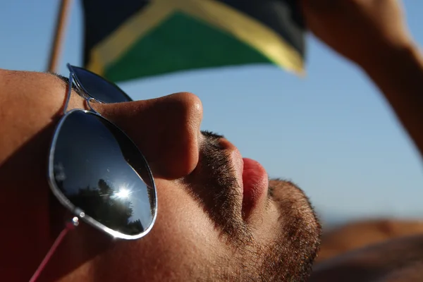 Mannen i solglasögon håller Jamaicas flagga — Stockfoto
