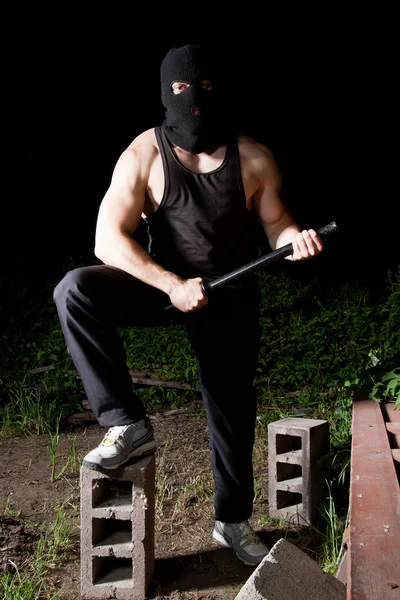 Gangster with baton outdoors at night — Stock Photo, Image