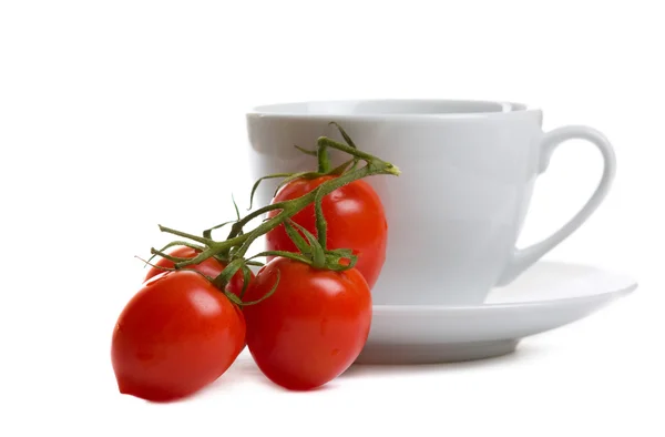 Branch of tomatoes and white cup — Stock Photo, Image