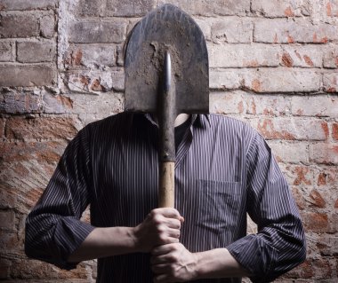 A man hides his face behind a shovel. clipart