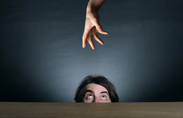El hombre mira desde detrás de su escritorio, escondiéndose — Foto de Stock
