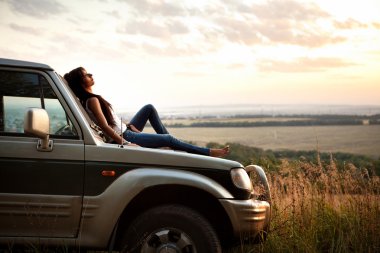 Woman is laying on the car's hood clipart