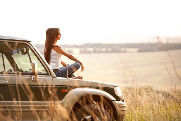 Kvinna sitter på bilens huv — Stockfoto
