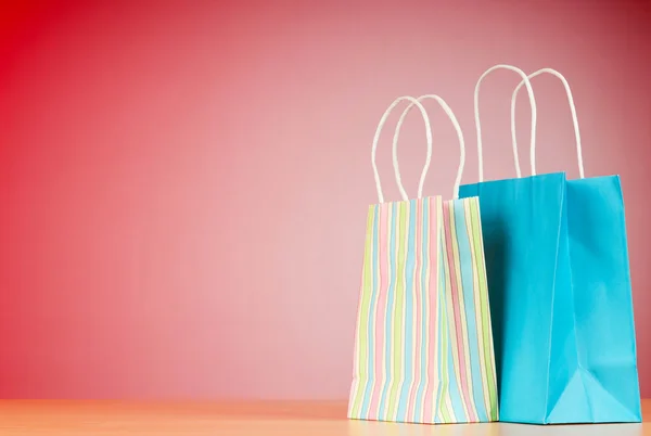 ग्रेडिएंट पृष्ठभूमि के खिलाफ रंगीन पेपर शॉपिंग बैग — स्टॉक फ़ोटो, इमेज