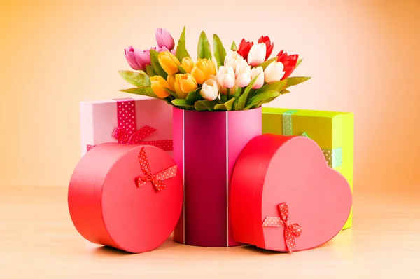Geschenkdoos en tulpen tegen achtergrond met kleurovergang — Stockfoto