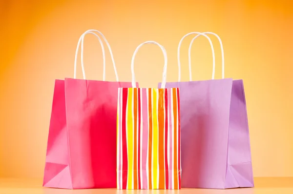 Sacos de compras de papel coloridos contra fundo gradiente — Fotografia de Stock