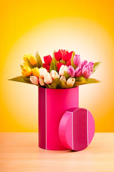 Geschenkbox und Tulpen vor Gradientenhintergrund — Stockfoto