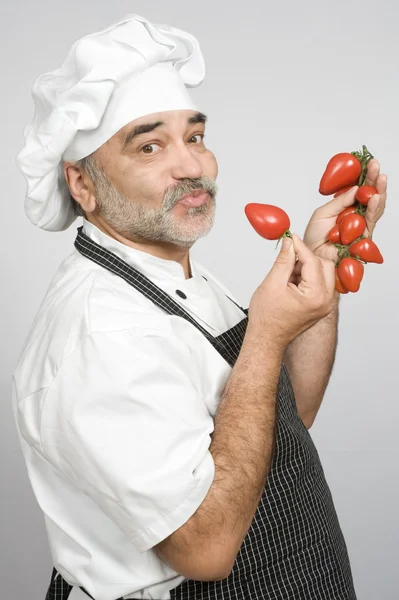 Chef sorridente con pomodori — Foto Stock
