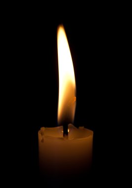 Burning candle on a black background clipart