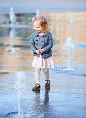 Little girl playing in street fountain clipart