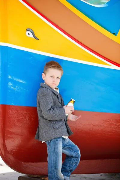 Мальчик рядом с красочной лодкой — стоковое фото
