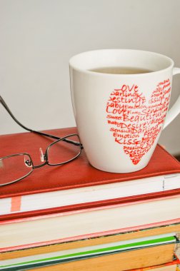Pile of old books, glasses and a cup of tea clipart