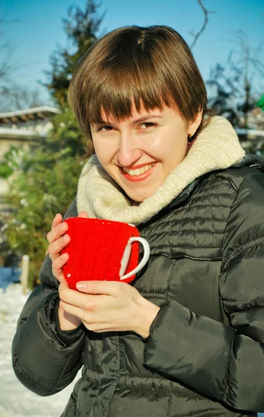 Young woman drinking hot tea outdoors in snowy garden — Stock Photo, Image
