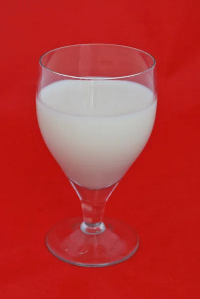 Glas färsk mjölk isolerad på röd bakgrund — Stockfoto