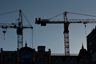 Silhouettes of elevating cranes clipart