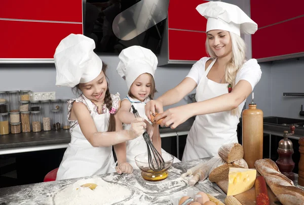 Moeder en twee dochters in de keuken — Stockfoto