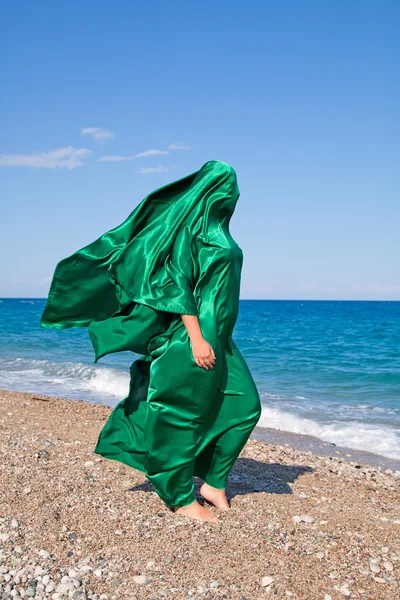 Meisje silhouet onder groene weefsel op het strand — Stockfoto