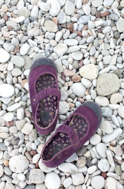 Woman shoes on the beach stones clipart