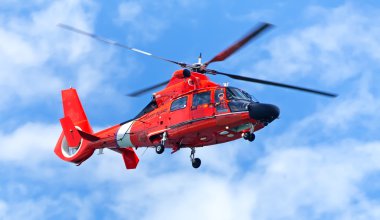 Red rescue helicopter moving in blue sky clipart