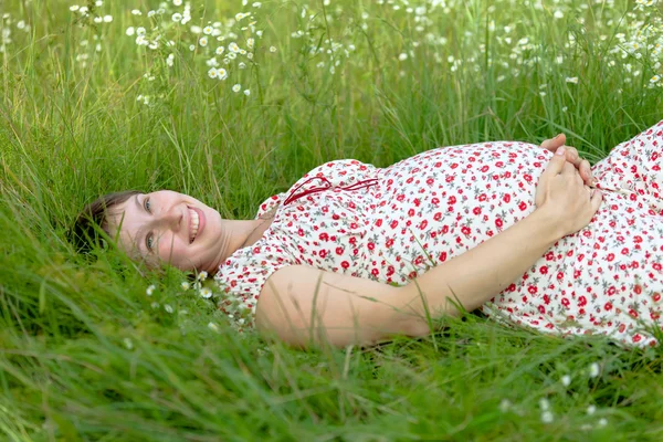 Těhotná žena leží v heřmánku — Stock fotografie