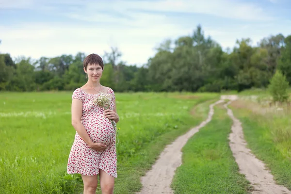 Těhotná žena s heřmánku kytice — Stock fotografie