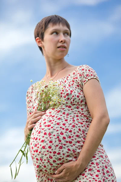 Worried pregnant woman with chamomile bouquet — Stock Photo, Image