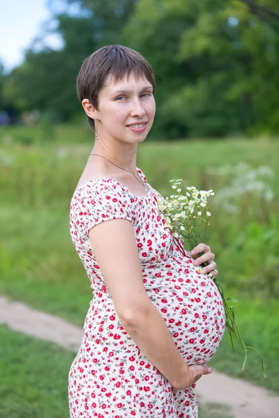 Těhotná žena s heřmánku kytice — Stock fotografie