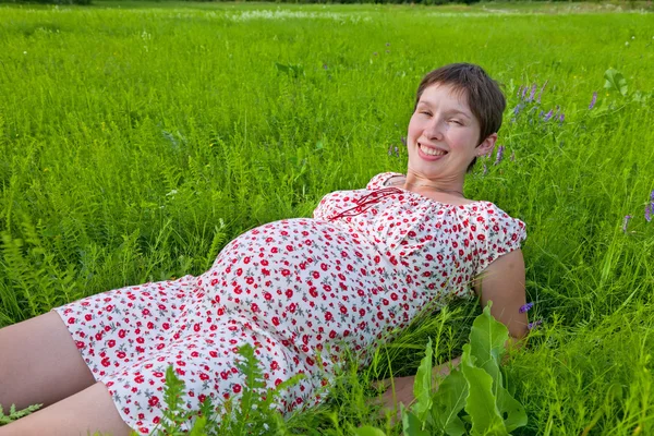Femme enceinte allongée sur l'herbe — Photo