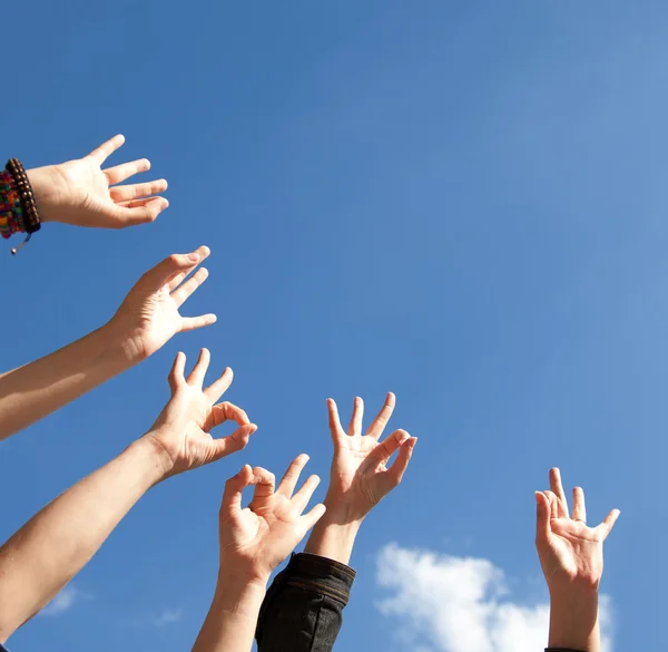 Mãos erguidas no ar através do céu — Fotografia de Stock