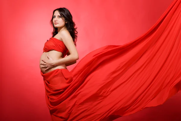 Těhotná žena na červené — Stock fotografie
