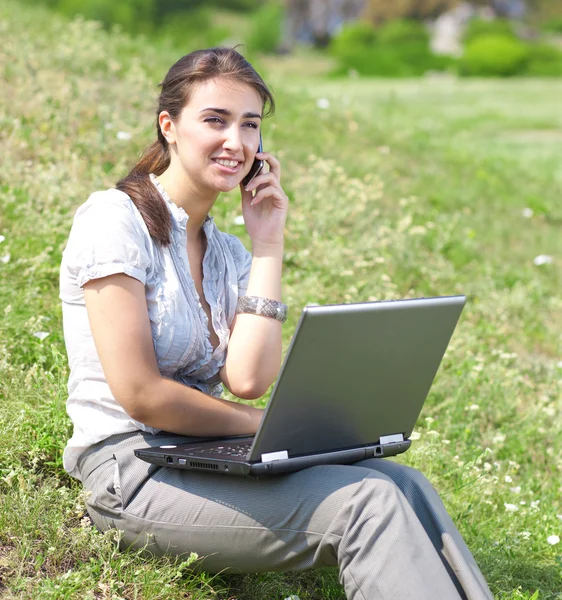 Kobieta z notebooka siedzieć na trawie — Zdjęcie stockowe