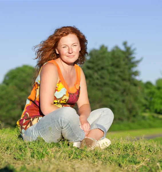 Donna seduta sull'erba nel parco — Foto Stock