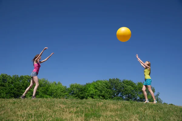 Two girls play with yellow ball — Stock Photo, Image