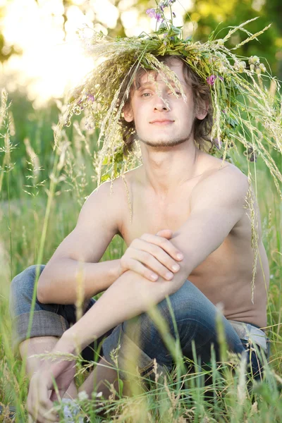 Молодой человек сидит на траве — стоковое фото
