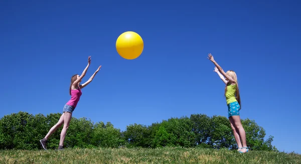 Two girls play with yellow ball — Stock Photo, Image