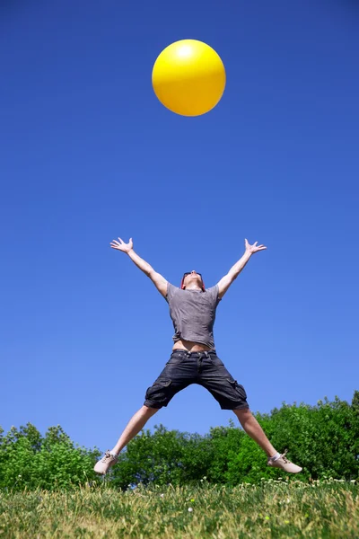 Молодой человек прыгает с желтым шариком — стоковое фото