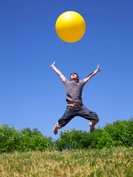 Młody człowiek skakać z żółtą kulką — Zdjęcie stockowe