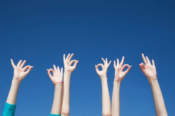 Gruppo di alzare le mani in aria attraverso il cielo blu — Foto Stock