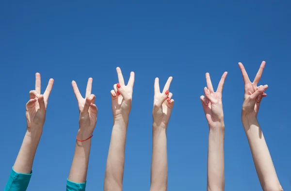 Grupo de levantar as mãos no ar através do céu azul — Fotografia de Stock