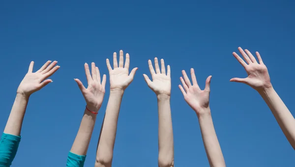 Ομάδα αύξηση τα χέρια στον αέρα σε όλη την μπλε ουρανό — Φωτογραφία Αρχείου
