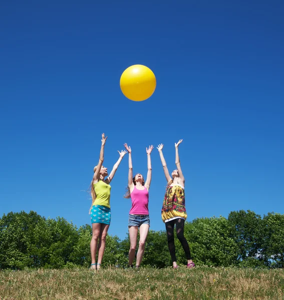Three girls play with yellow ball — Stock Photo, Image