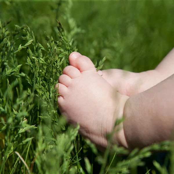 Baby voet op groen gras — Stockfoto
