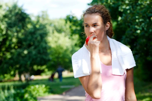 Молодая женщина после спортивных тренировок едят яблоко — стоковое фото