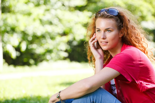Kobieta rozmawiać przez telefon w parku — Zdjęcie stockowe