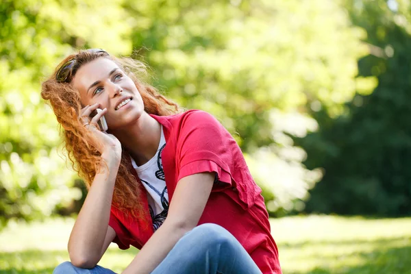 Woman talking over the phone in park — Stock Photo, Image