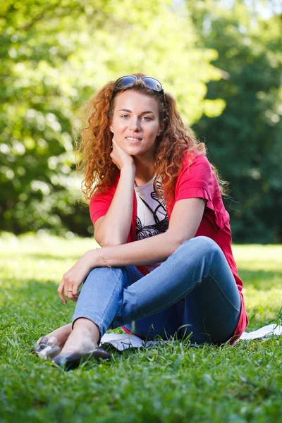 Donna seduta sull'erba nel parco — Foto Stock